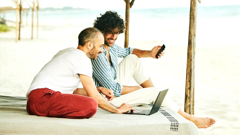 Traveller using a laptop and phone while sitting by a window